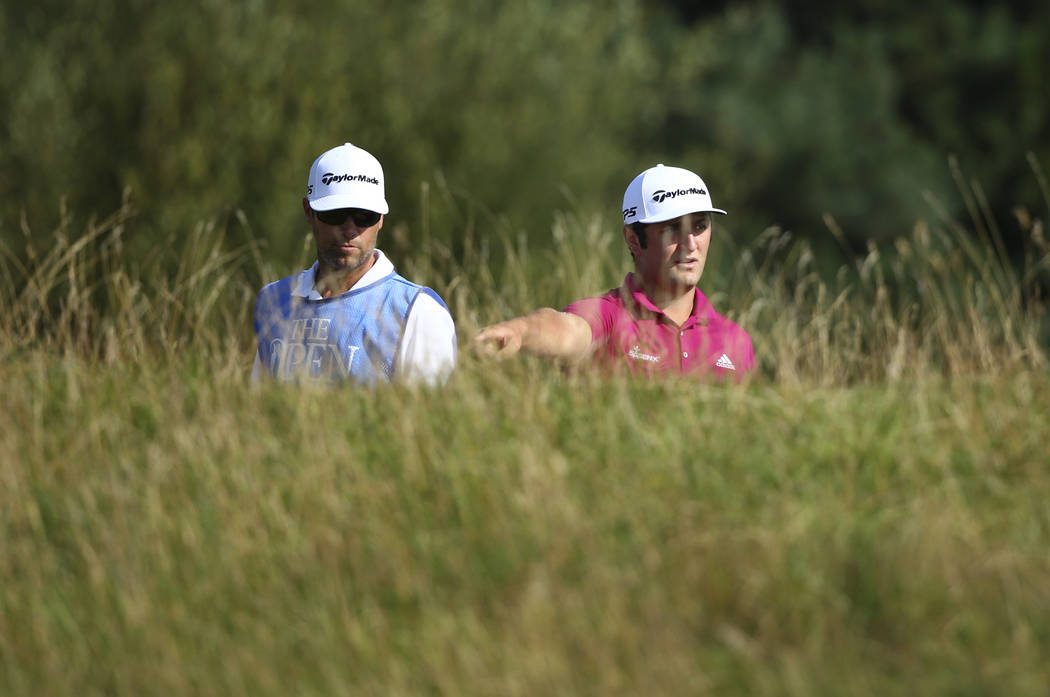 Spain's Jon Rahm, right, prepares to play from the rough on the 6th hole during a practice round ahead of the British Open Golf Championship, at Royal Birkdale, Southport, England Tuesday, July 18 ...