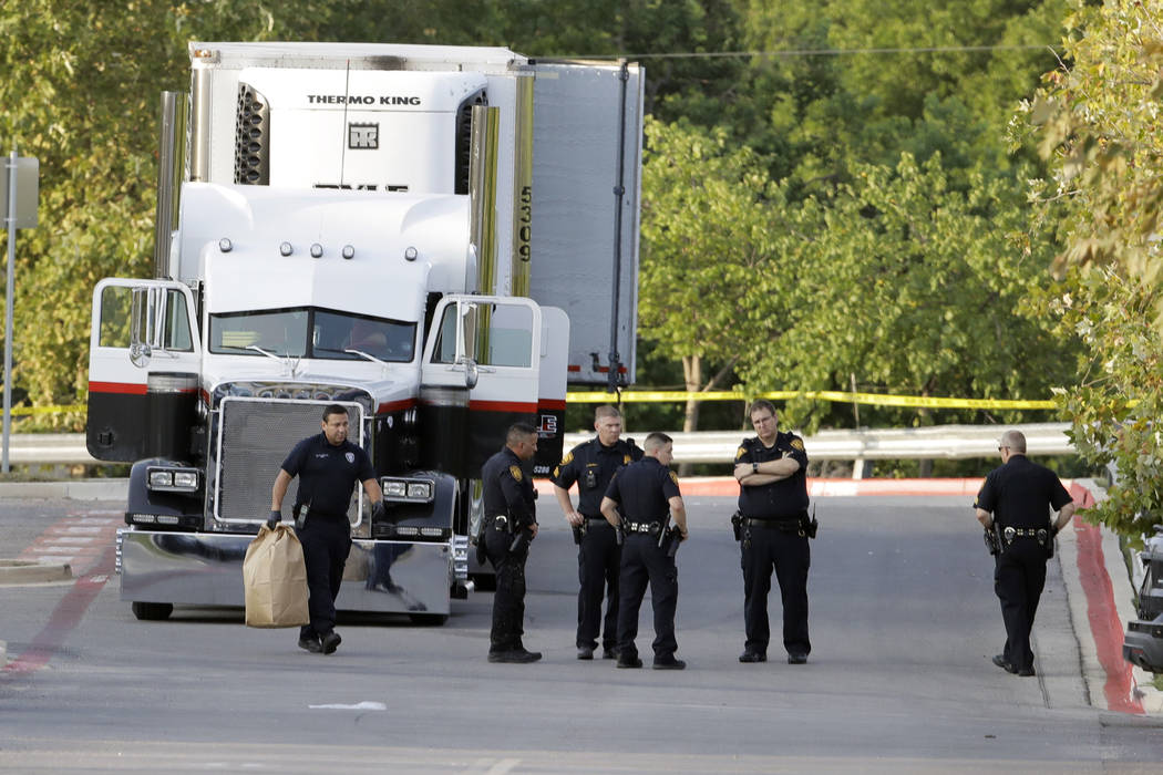 San Antonio police officers investigate the scene Sunday, July 23, 2017, where eight people were found dead in a tractor-trailer loaded with at least 30 others outside a Walmart store in stifling  ...