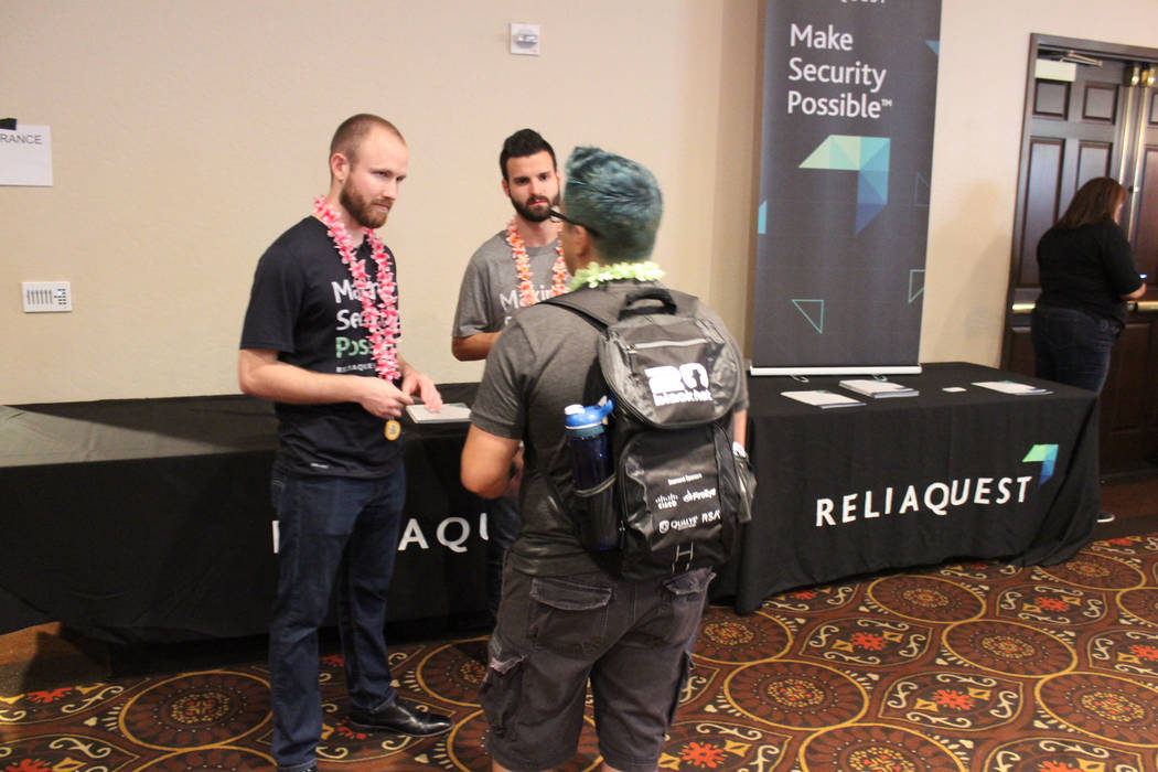 ReliaQuest Business Analyst Jimmy Benoit (left) and Network Security Engineer Zac Attia speak with a cybersecurity professional at ReliaQuest’s booth at the BSides Las Vegas Wednesday, July 26,  ...