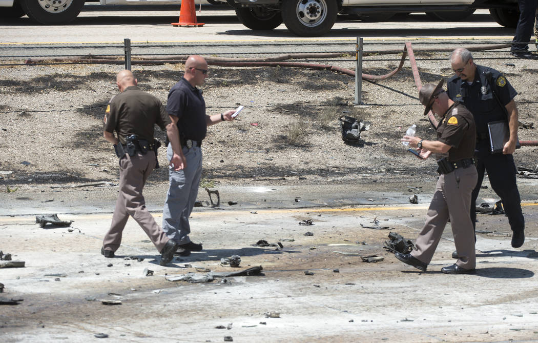 Police sort through the debris from the plane crash that killed four people in the median of I-15 near Riverdale, Utah, Wednesday, July 26, 2017. The crash closed the freeway to northbound traffic ...