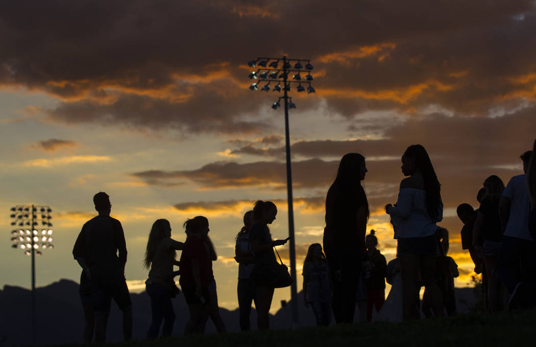 People are silhouetted against the sky after a vigil for Haylei Hughes, a former Cimarron-Memorial student-athlete, who died in a hiking accident in Wash., at Kellogg Zaher Sports Complex in Las V ...