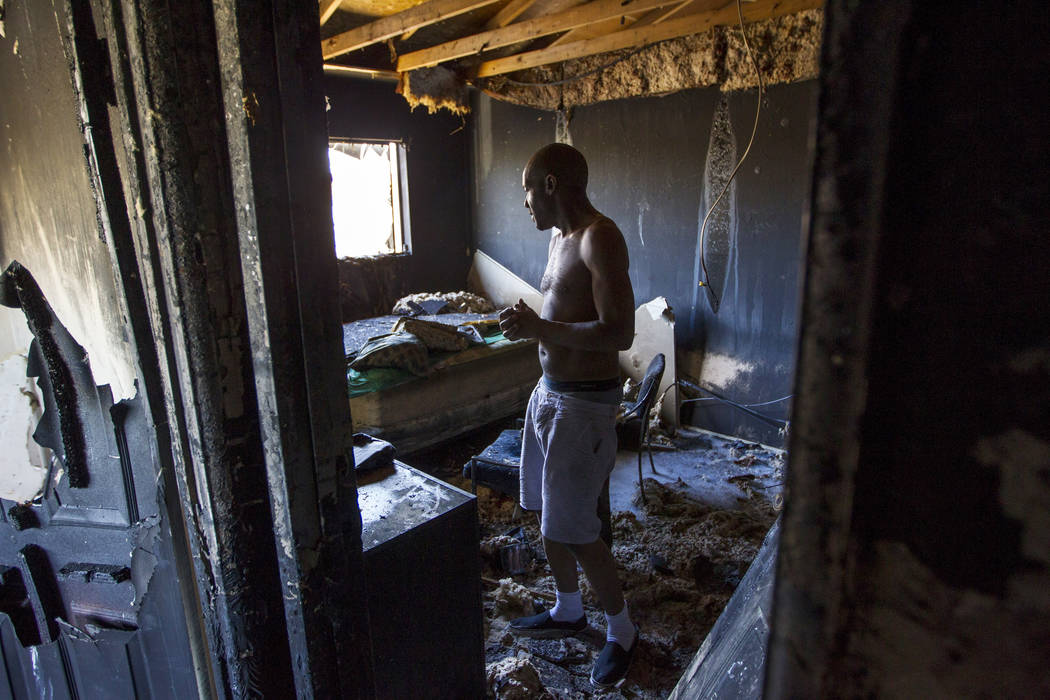 Mulberry Park Apartments resident Chris Cooper walks through his bedroom looking to salvage any personal belongings after his apartment was destroyed in an early morning kitchen fire on Friday, Ju ...