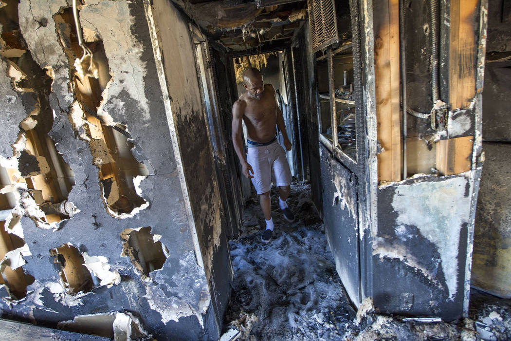Mulberry Park Apartments resident Chris Cooper walks through his hallway looking to salvage any personal belongings after his apartment was destroyed in an early morning kitchen fire on Friday, Ju ...