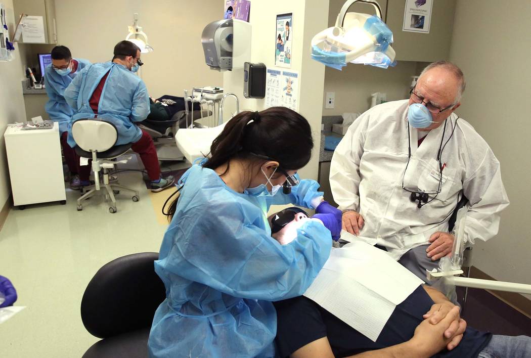 Richard Schoen, right, Asst. Professor, UNLV School of Dental Medicine, supervises as UNLV volunteer dental students treat patients at Volunteers In Medicine of Southern Nevada on Monday, July 24, ...