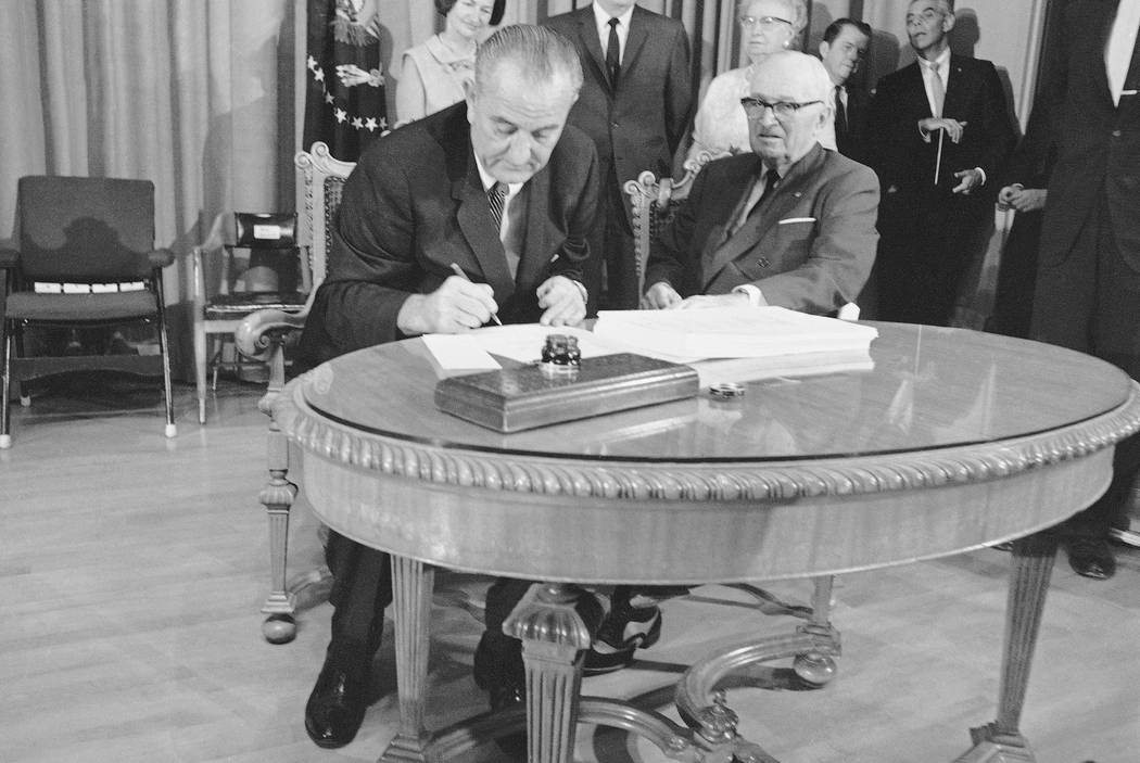 With former Pres. Harry S. Truman at his side, President Lyndon B. Johnson uses the last of many pens to complete the signing of the Medicare Bill into law at ceremonies at the Truman Library in I ...