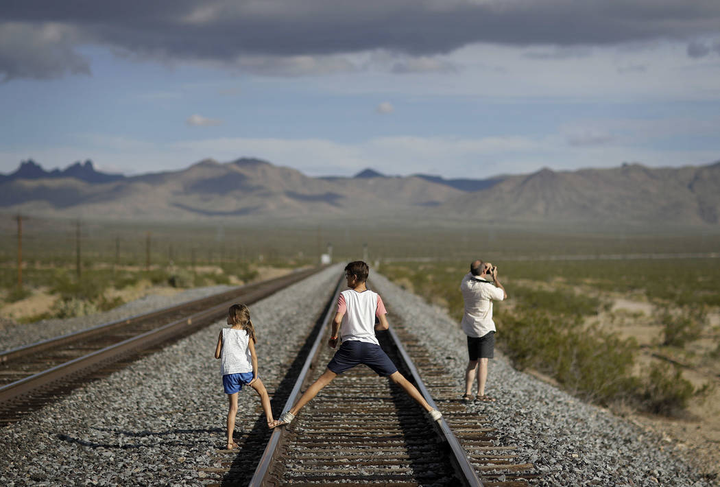 A family walks along train tracks, Thursday, Aug. 3, 2017, in Nipton, Calif. One of the nation's largest cannabis companies announced it has bought the entire 80 acre California desert town of Nip ...