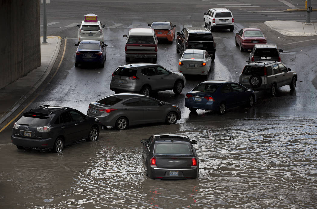 Drivers attempt to navigate a flooded area, where a car is already stuck in the water, near the intersection of Dean Martin Drive and West Twain Ave on Friday, Aug. 4, 2017, in Las Vegas. Bridget ...