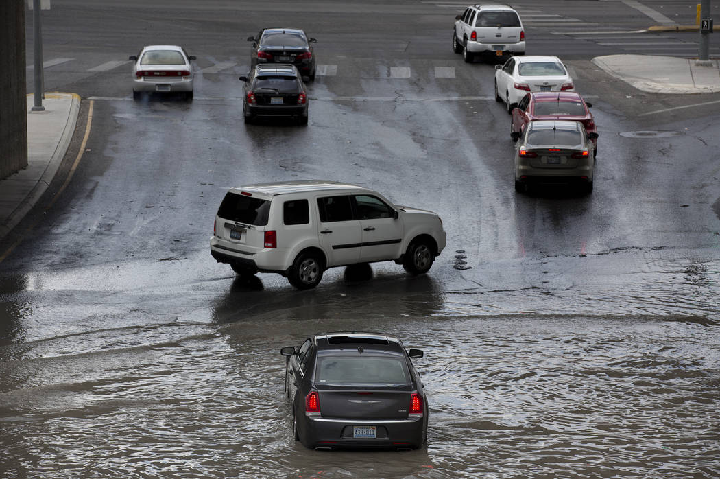 Drivers attempt to navigate a flooded area, where a car is already stuck in the water, near the intersection of Dean Martin Drive and West Twain Ave on Friday, Aug. 4, 2017, in Las Vegas. Bridget  ...