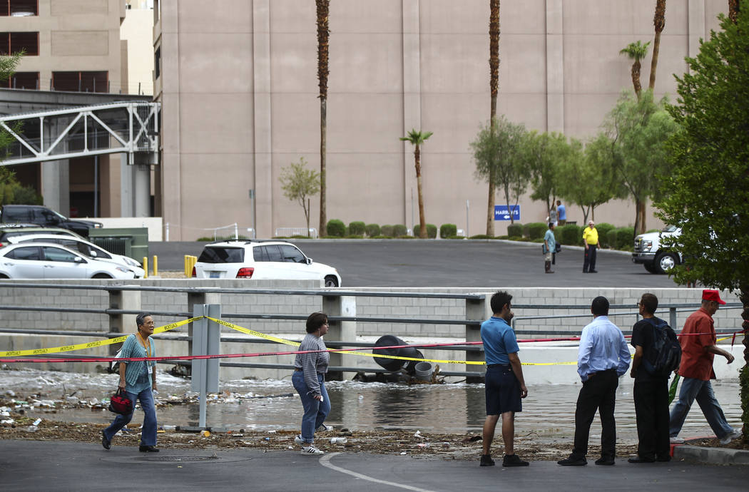 People pass by debris near the wash behind The Linq Hotel in Las Vegas on Friday, Aug. 4, 2017. Six people were rescued from the wash. Chase Stevens Las Vegas Review-Journal @csstevensphoto