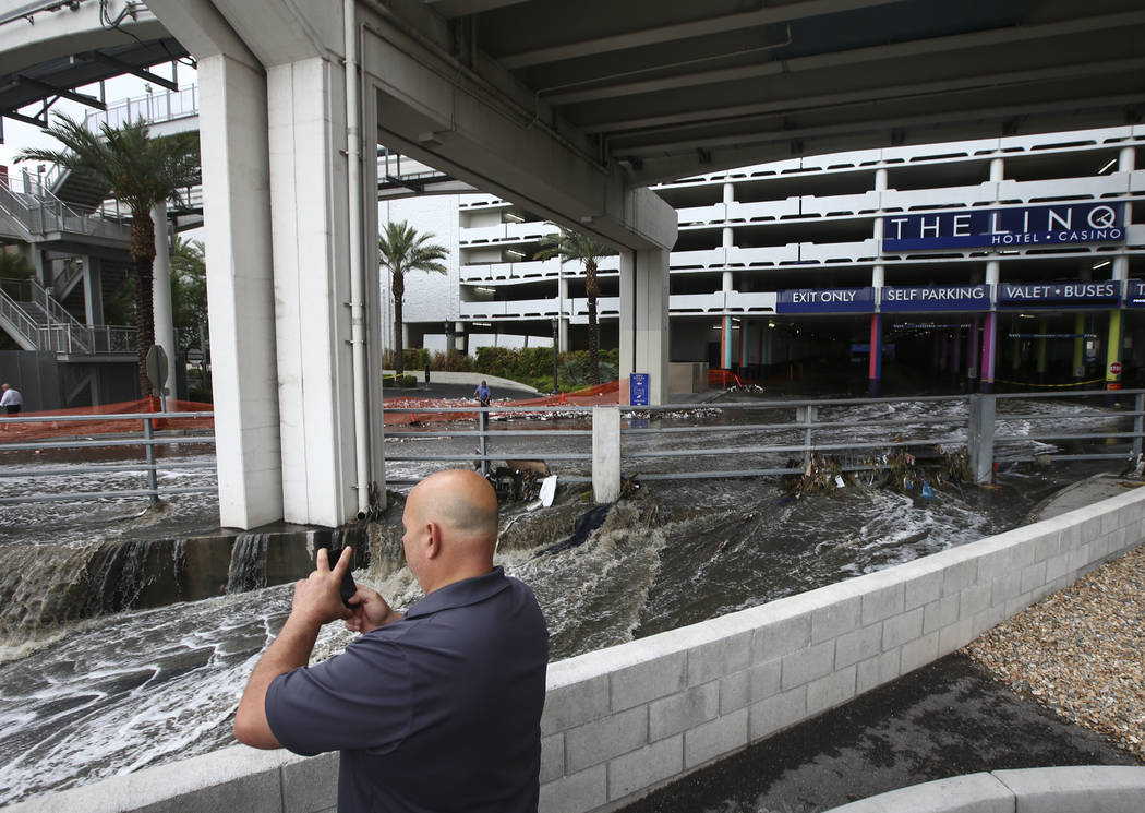A man records water flowing through the wash behind The Linq Hotel in Las Vegas on Friday, Aug. 4, 2017. Six people were rescued from the wash. Chase Stevens Las Vegas Review-Journal @csstevensphoto