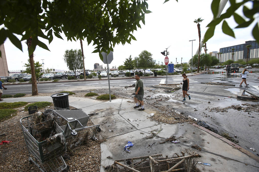People pass by debris near the wash behind The Linq Hotel in Las Vegas on Friday, Aug. 4, 2017. Six people were rescued from the wash. Chase Stevens Las Vegas Review-Journal @csstevensphoto