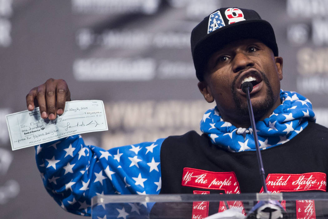 Boxer Floyd Mayweather Jr., shows his 2015 check from his fight against Manny Pacquiao during a world tour event to promote his upcoming fight against UFC fighter Conor McGregor, at Staples Center ...