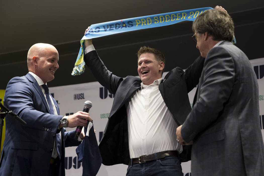 United Soccer League president Jake Edwards, left, and CEO Alec Papadakis, right, look on as Brett Lashbrook, founder of Las Vegas Soccer LLC, celebrates his new Las Vegas soccer team to play in t ...