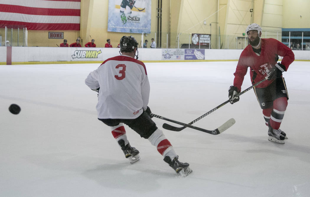 Deryk Engelland, right, of the Las Vegas Golden Knights, passes a puck past Adam Naglich, left,  during the Fifth Annual Charity Ice Hockey game at the Sobe Ice Arena at the  Fiesta Rancho Hotel & ...