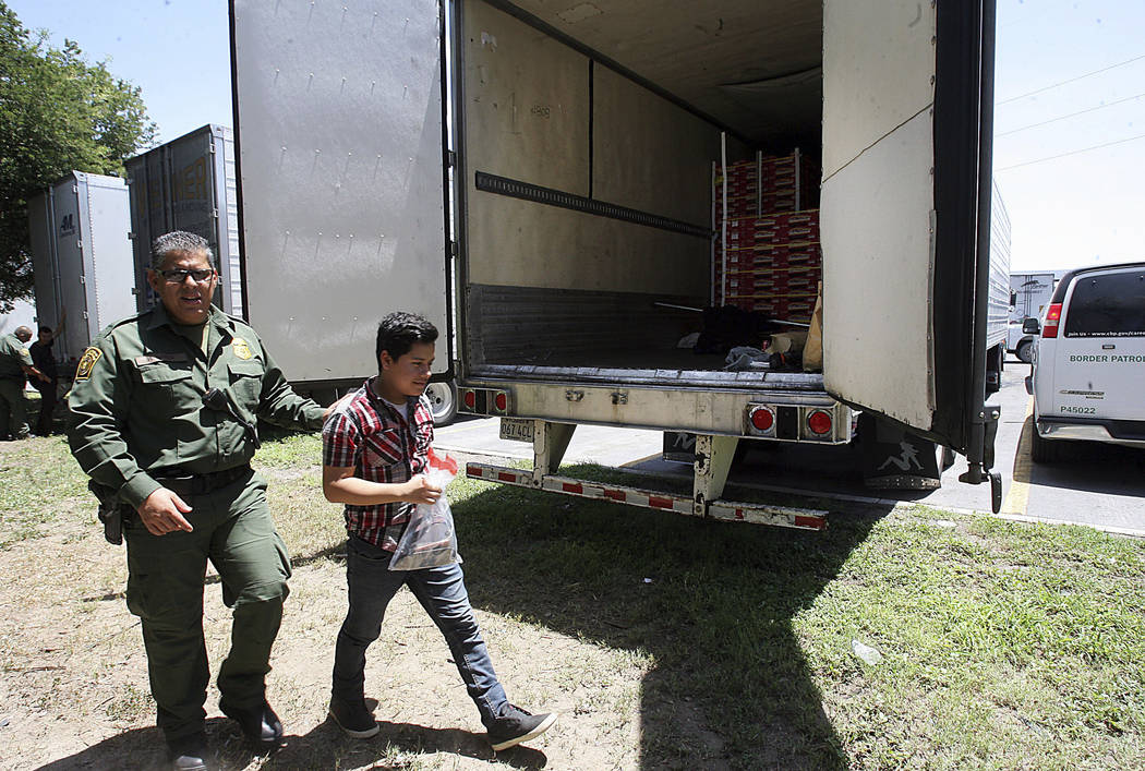 Border Patrol officers escort a group of immigrants to a van in Edinburg, Texas, Sunday, Aug. 13, 2017. Police in Texas acting on a tip found the immigrants locked inside the tractor-trailer parke ...