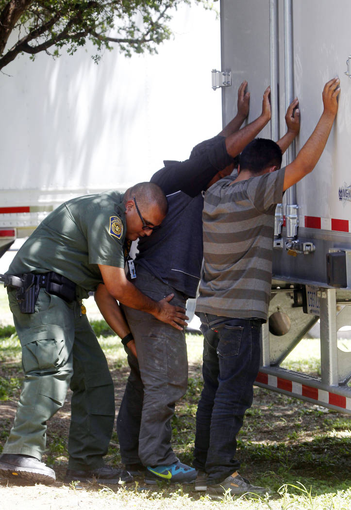 A Border Patrol officer pats down several of the men that were found with a group of immigrants in a tractor-trailer Sunday, Aug. 13, 2017, in Edinburg, Texas. (Delcia Lopez/The Monitor via AP)