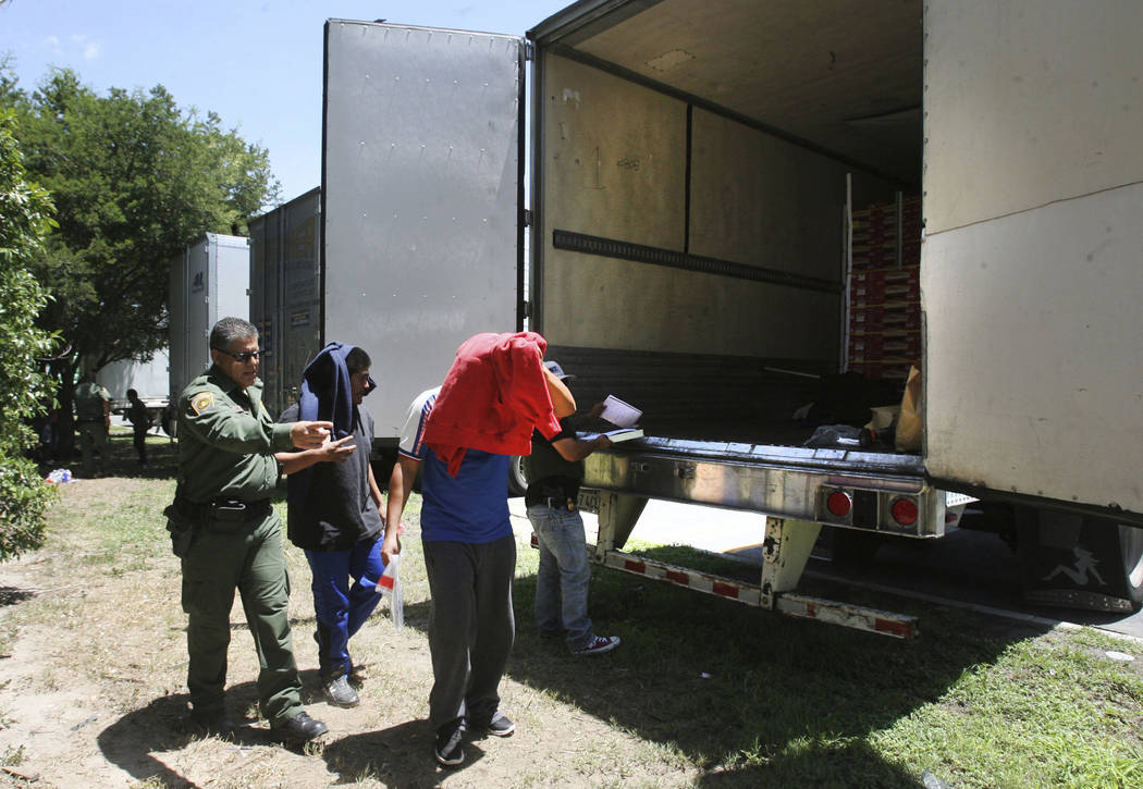 Border Patrol officers escort a group of immigrants to a van after a group was found in the tractor-trailer Sunday, Aug. 13, 2017, in Edinburg, Texas. (Delcia Lopez/The Monitor via AP)