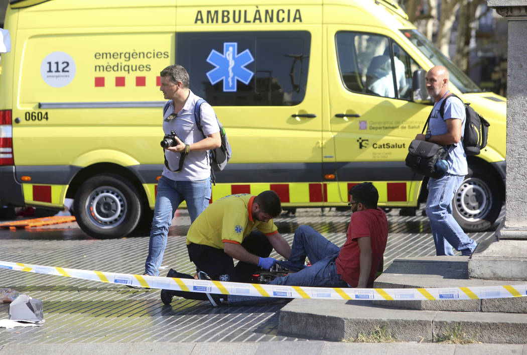 An injured person is treated in Barcelona, Spain, Thursday, Aug. 17, 2017 after a white van jumped the sidewalk in the historic Las Ramblas district, crashing into a summer crowd of residents and  ...