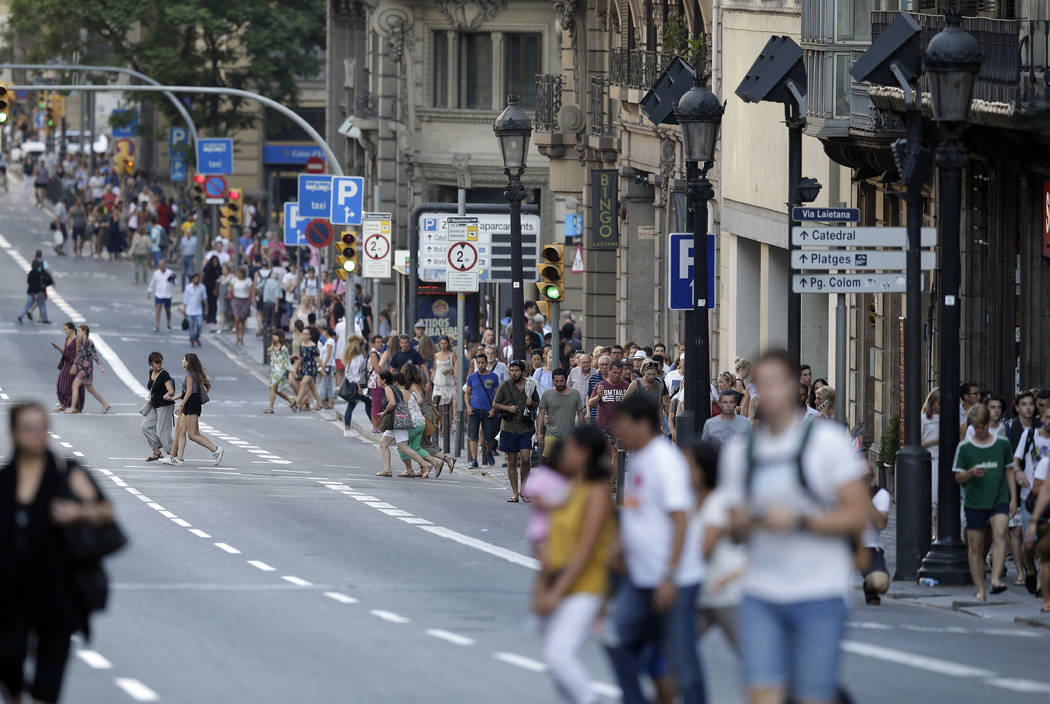 People walk down a main street in Barcelona, Spain, Thursday, Aug. 17, 2017. Police in Barcelona say a white van has mounted a sidewalk, struck several people in the city's Las Ramblas district. ( ...