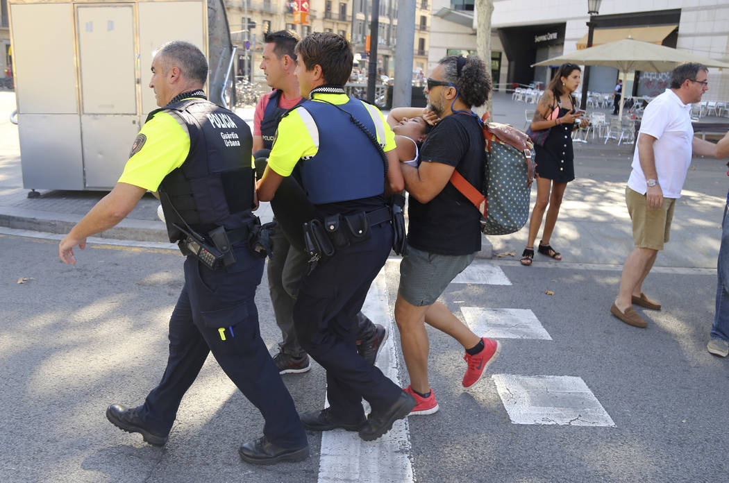 An injured person is carried in Barcelona, Spain, Thursday, Aug. 17, 2017 after a white van jumped the sidewalk in the historic Las Ramblas district, crashing into a summer crowd of residents and  ...