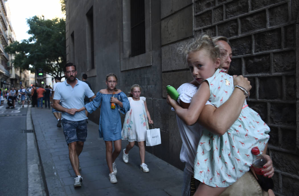 People flee the scene in Barcelona, Spain, Thursday, Aug. 17, 2017 after a white van jumped the sidewalk in the historic Las Ramblas district, crashing into a summer crowd of residents and tourist ...