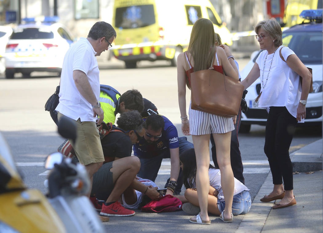 An injured person is treated in Barcelona, Spain, Thursday, Aug. 17, 2017 after a white van jumped the sidewalk in the historic Las Ramblas district, crashing into a summer crowd of residents and  ...