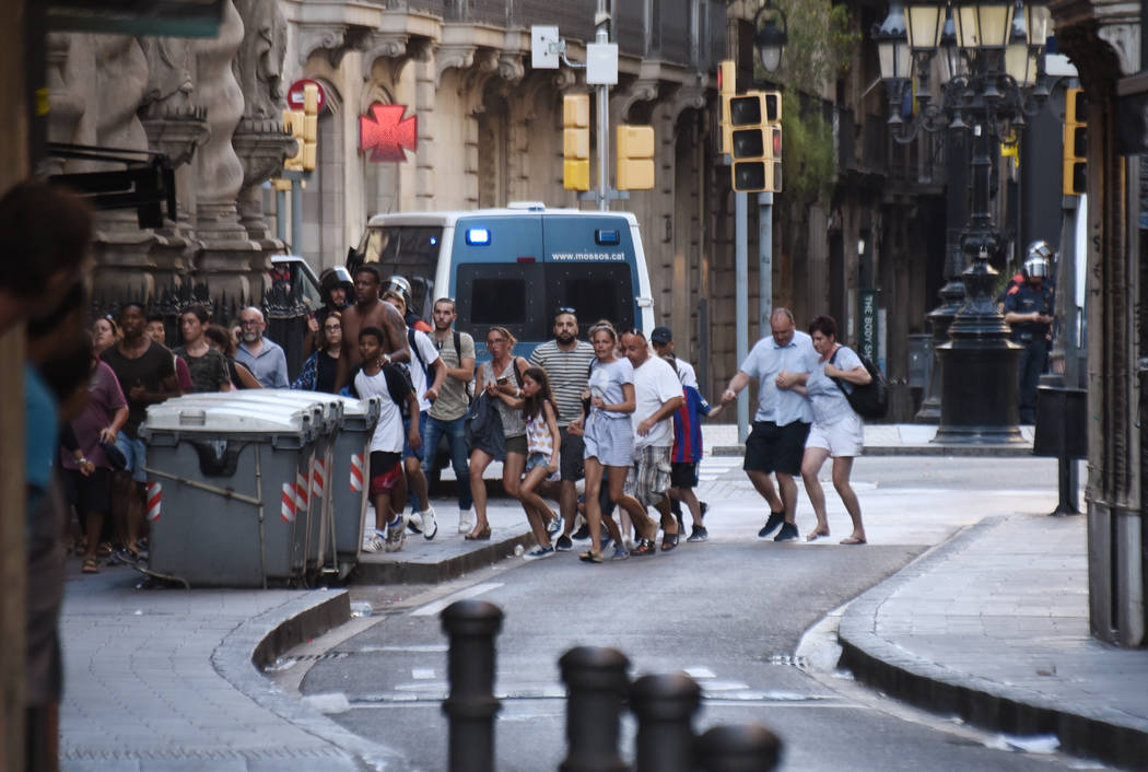 People flee from the scene after a white van jumped the sidewalk in the historic Las Ramblas district of Barcelona, Spain, crashing into a summer crowd of residents and tourists Thursday, Aug. 17, ...