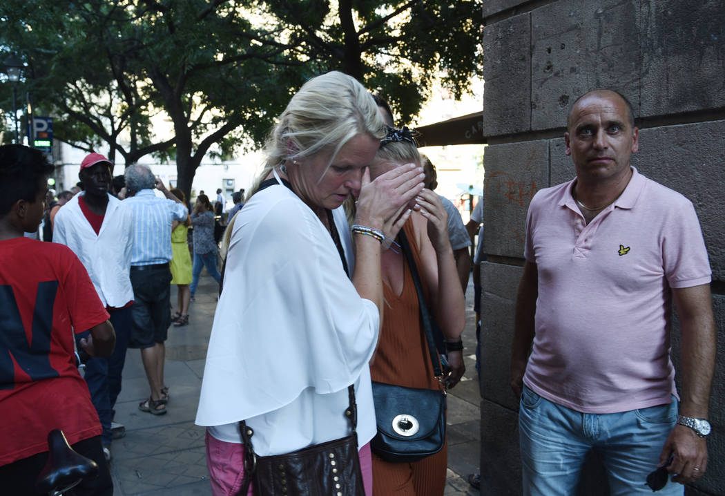 A woman is comforted as crowds flee from the scene after a white van jumped the sidewalk in the historic Las Ramblas district of Barcelona, Spain, crashing into a summer crowd of residents and tou ...