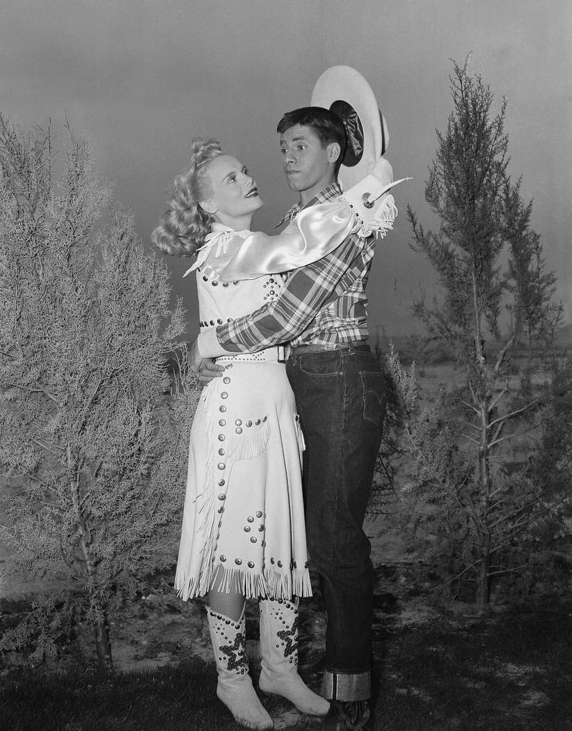 In a spot most men would envy, Jerry Lewis appears quite at a loss in the face of amorous advances on the part of actress Marie Wilson during filming on location on April 11, 1950, at Las Vegas. (AP)