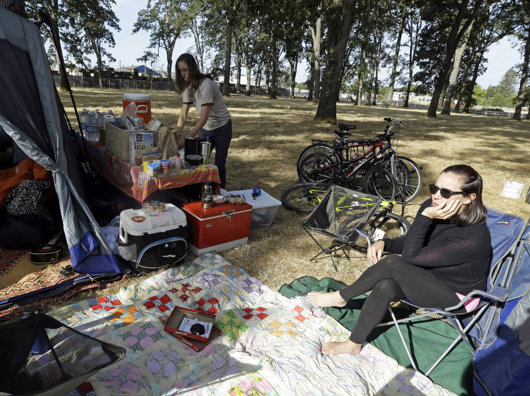 Hilary O'Hollaren, right, sits in the early morning sun as Rory O'Hollaren prepares breakfast as they camp near the state fairgrounds in preparation for the Aug. 21, 2017, solar eclipse in Salem,  ...
