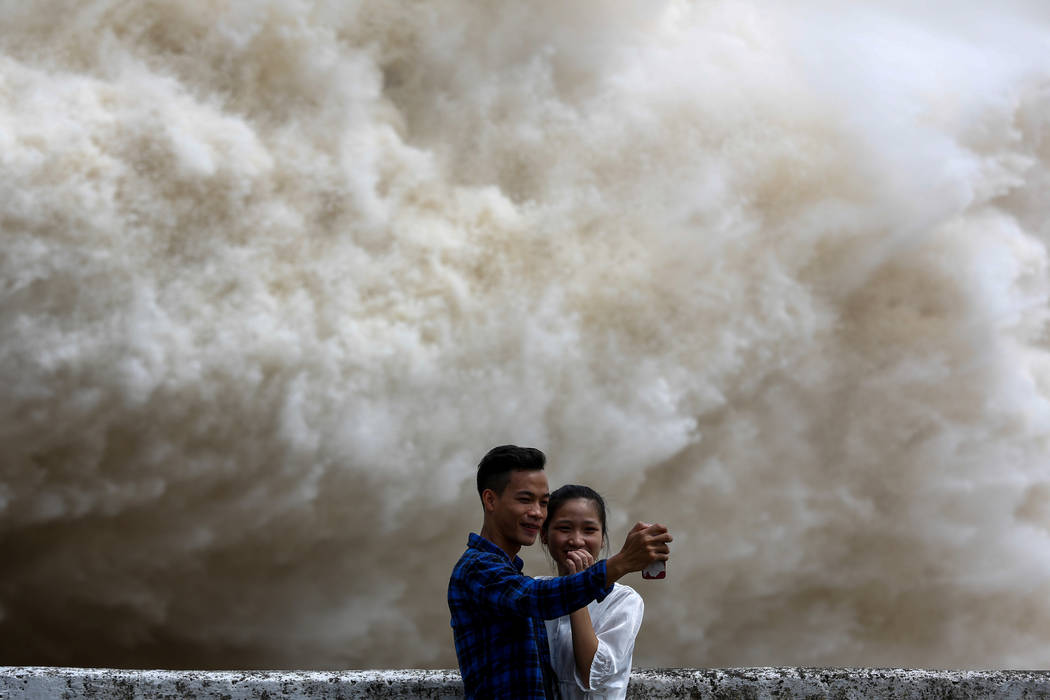 A couple takes a selfie as Hoa Binh hydroelectric power plant opens the flood gates after a heavy rainfall caused by Talas typhoon in Hoa Binh province, outside Hanoi, Vietnam July 20, 2017. REUTE ...