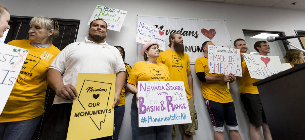 People hold signs during a news conference about Secretary Zinke's shortened visit to Nevada at a Battle Born Progress office in Las Vegas, Monday, July 31, 2017.  Zinke's shortened visit was bemo ...