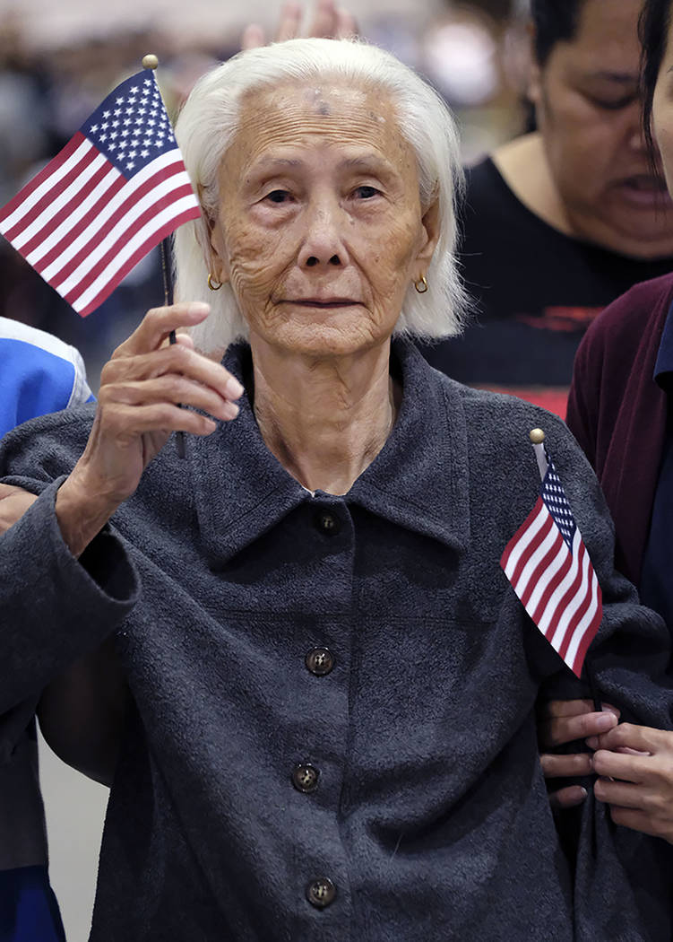 Hong Inh waves an American flag and smiles as she takes the oath to become a United States citizen at the Los Angeles Convention Center on Aug. 22. (AP Photo/Richard Vogel)