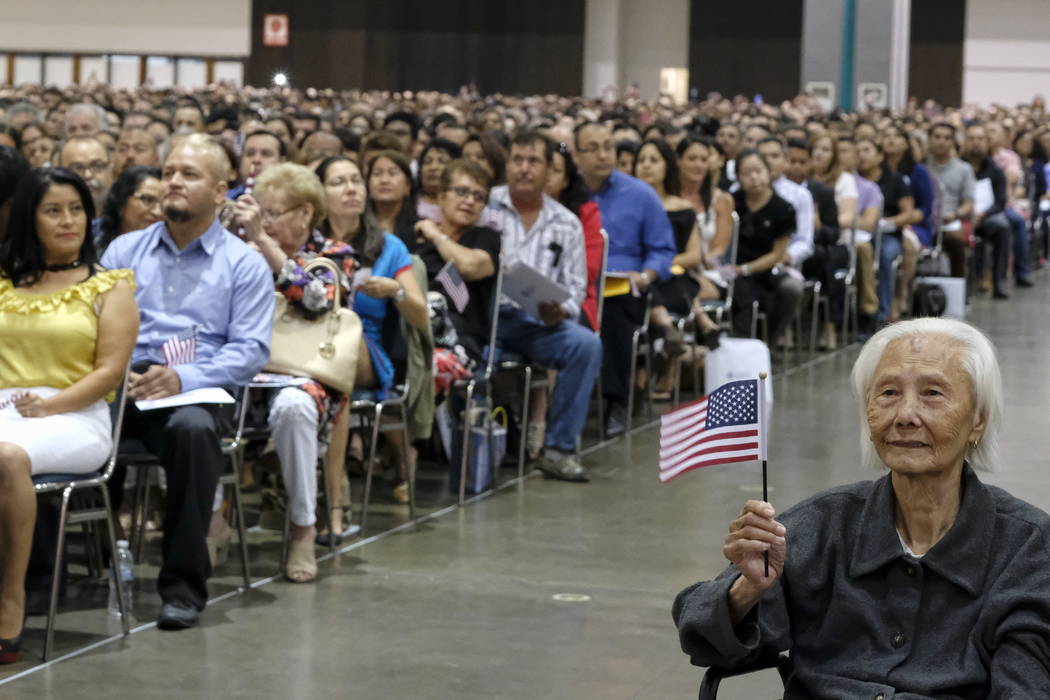Hong Inh, right, waves an American flag during a ceremony to become a United States citizen at the Los Angeles Convention Center on Aug. 22. (AP Photo/Richard Vogel)