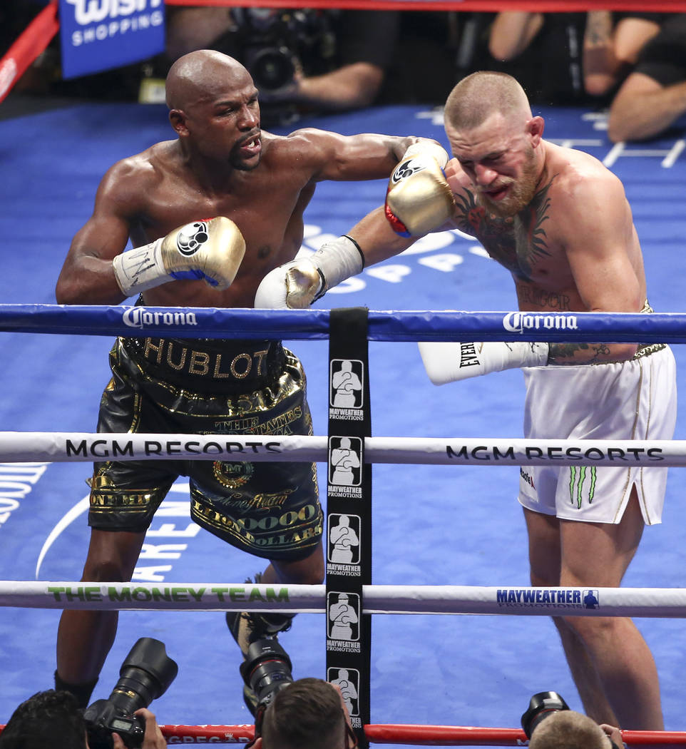 Floyd Mayweather Jr., left, delivers the final blows to Conor McGregor in their super welterweight fight at T-Mobile Arena, Saturday, Aug. 26, 2017, in Las Vegas. Mayweather won via 10th round tec ...