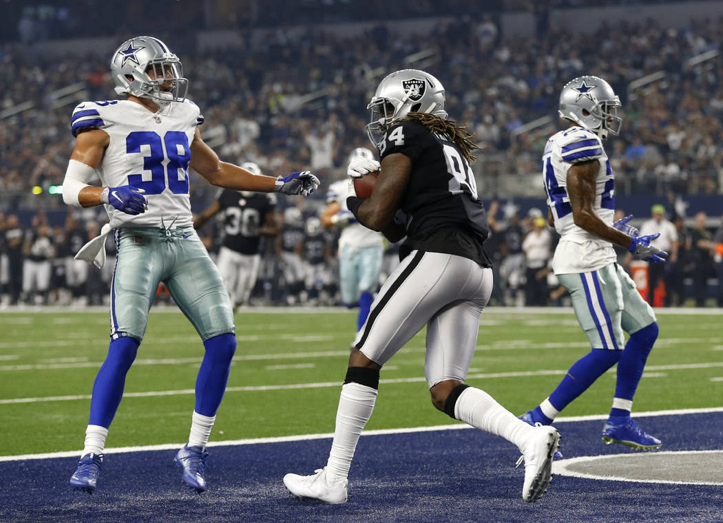 Oakland Raiders wide receiver Cordarrelle Patterson (84) catches a touchdown pass between Dallas Cowboys' Jeff Heath (38) and Nolan Carroll II, right, in the first half of a preseason NFL football ...