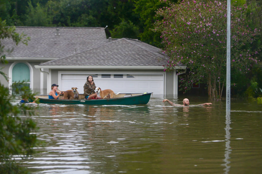A family evacuates their Meyerland home in Houston, Sunday, Aug. 27, 2017.  Rescuers answered hundreds of calls for help Sunday as floodwaters from the remnants of Hurricane Harvey rose high enoug ...