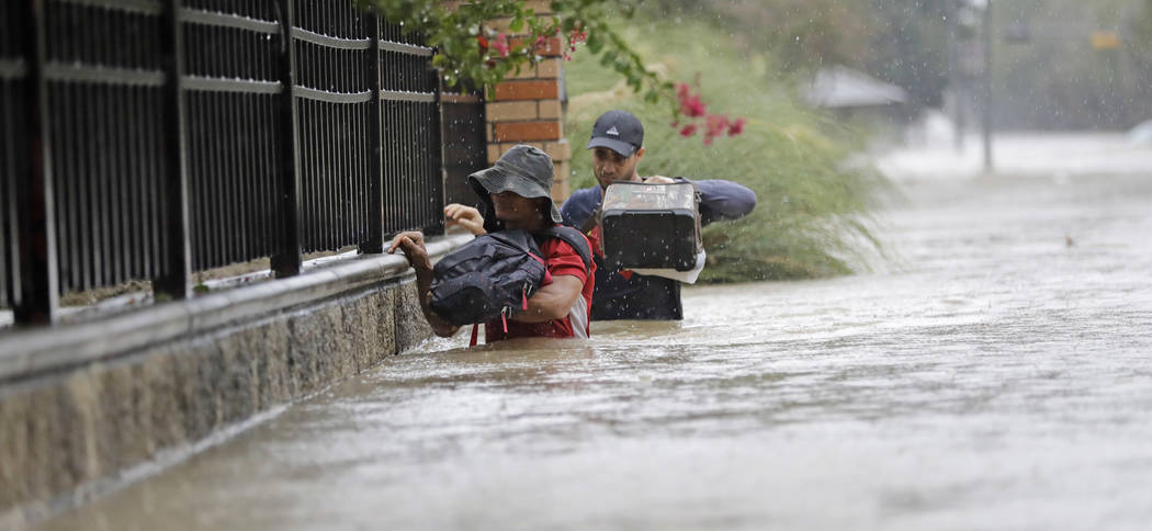 Residents wade through floodwaters from Tropical Storm Harvey Sunday, Aug. 27, 2017, in Houston, Texas. (David J. Phillip/AP)