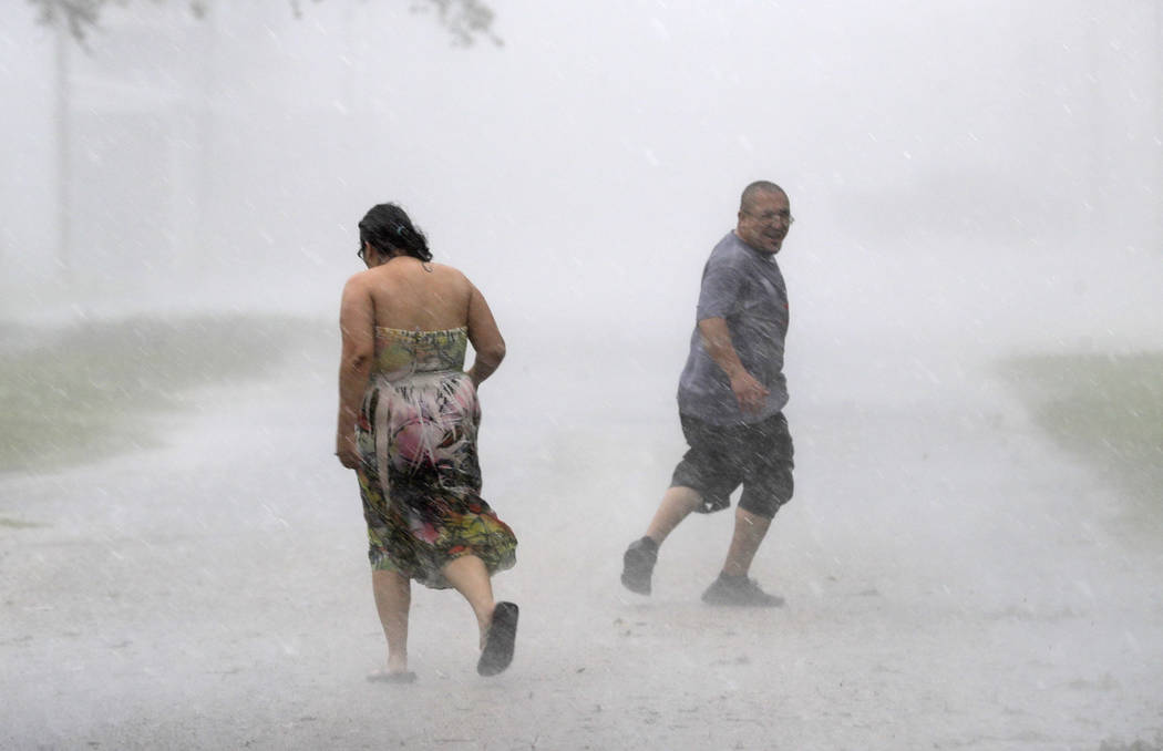 Antonio Barron, right, looks back to his girlfriend, Melissa Rocha, as they run through the street during a band of heavy rain from Hurricane Harvey Saturday, Aug. 26, 2017, in Palacios, Texas. (D ...