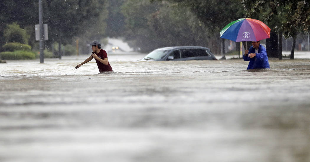 Moses Juarez, left, and Anselmo Padilla wade through floodwaters from Tropical Storm Harvey on Sunday, Aug. 27, 2017, in Houston, Texas. (David J. Phillip/AP)