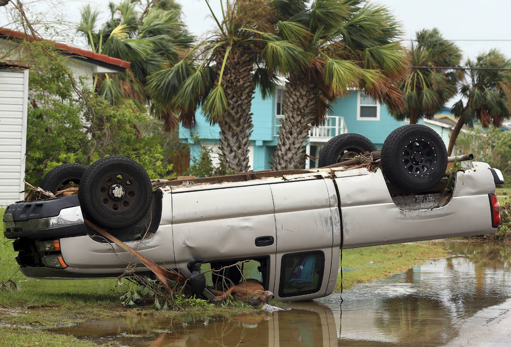 A dead dog lies out of the passenger window of an overturned pickup truck after Hurricane Harvey landed in the Coast Bend area in Port Aransas, Texas, on Saturday, Aug. 26, 2017. Harvey came ashor ...