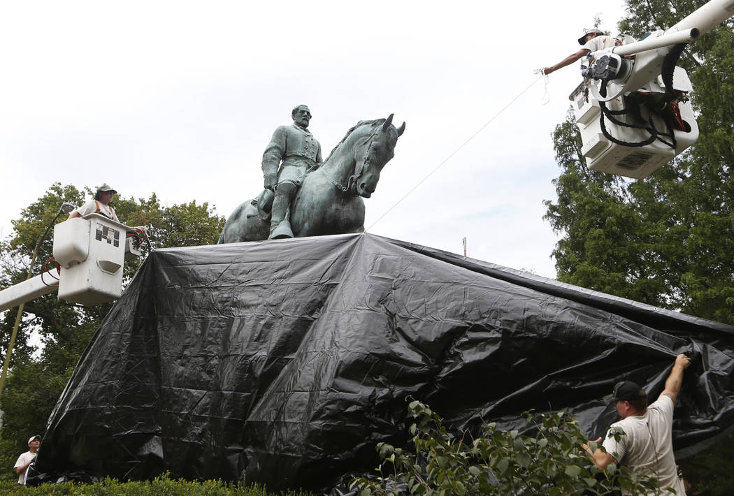 City workers drape a tarp over the statue of Confederate General Robert E. Lee in Emancipation park in Charlottesville, Virginia, Wednesday, Aug. 23, 2017. The move to cover the statues is intende ...