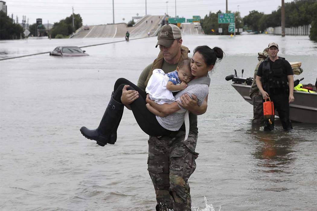 Houston Police SWAT officer Daryl Hudeck carries Catherine Pham and her 13-month-old son Aiden after rescuing them from their home surrounded by floodwater on Sunday, Aug. 27, 2017, in Houston. (D ...