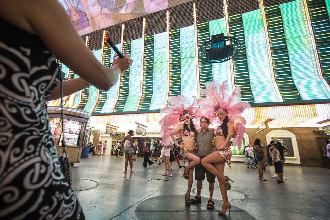 Felicia Vail, left, and Kelly Freesland, both of Showgirl Mafia, pose with Bruce Conrad of Illinois along the Fremont Street Experience in downtown Las Vegas on Wednesday, Aug. 2, 2017. Chase Stev ...