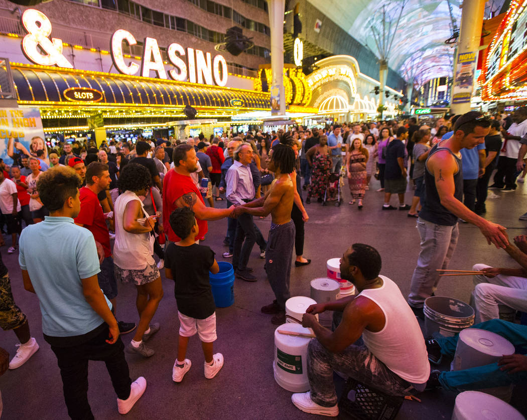 Buskers who go by the name Bucket Nation, referring the the buckets they drum on, mingle with tourists after performing along the Fremont Street Experience in downtown Las Vegas on Thursday, Aug.  ...