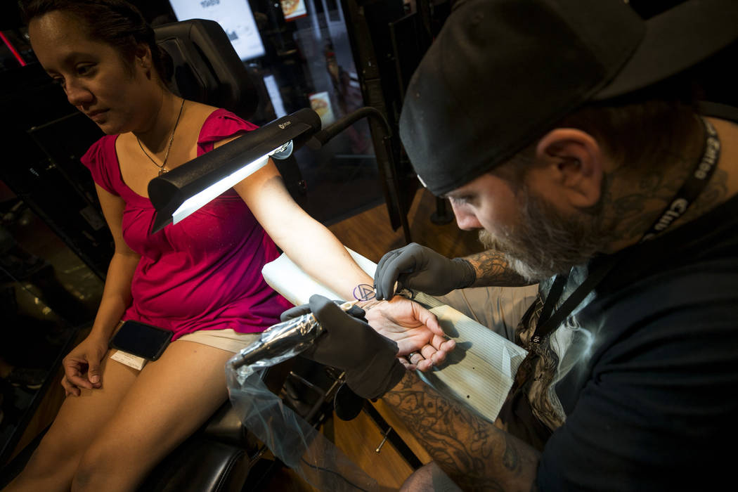 Linkin Park fan Jenny Jacobo gets a Linkin Park logo tattoo from artist Billy Greenway at Club Tattoo in Planet Hollywood on Saturday, Sept. 2, 2017, in Las Vegas. Linkin Park canceled their upcom ...