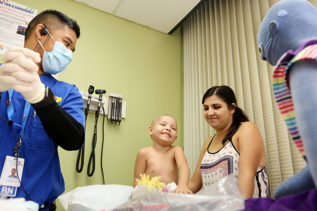 Leukemia patient Madilyn Cash, 4, holds her mother Marisa Velasco's hand while Nurse Branden Beria prepares to work at the Children's Specialty Center of Nevada in Las Vegas, Tuesday, Sept. 5, 201 ...