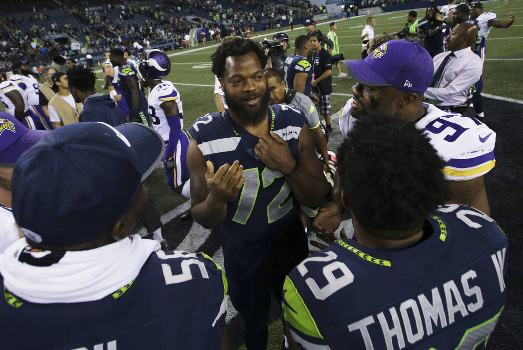 Seattle Seahawks defensive end Michael Bennett, center talks with teammate Earl Thomas and Minnesota Vikings' Everson Griffen, upper right, following an NFL football preseason game, Friday, Aug. 1 ...