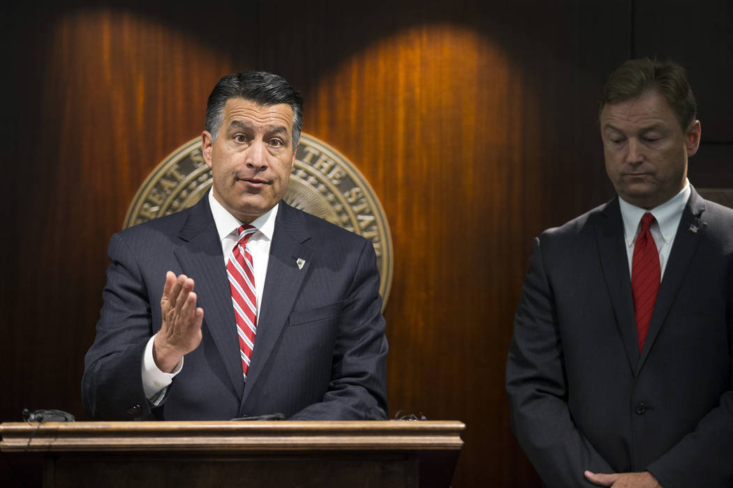 FILE - In this Friday, June 23, 2017 file photo, Gov. Brian Sandoval, left, and U.S. Sen. Dean Heller, R-Nev., give a news conference in Las Vegas where the senator announced he will vote no on th ...