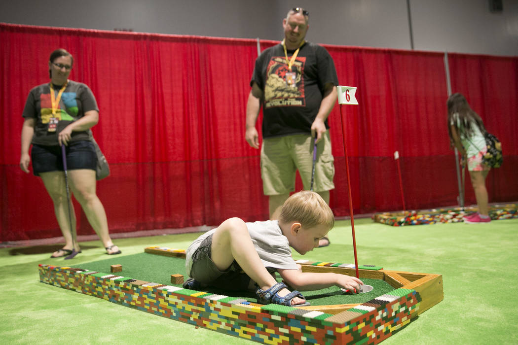 Ethan Schroth, de 3 años, en el centro, juega al minigolf mientras sus padres, Christine Schroth y Matthew Schroth, observan durante Brick Fest Live. en el Centro de Convenciones de Las Vegas en Las Vegas el sábado,